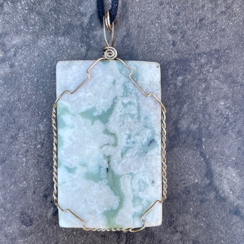 Wrapped stone pendant on cord.